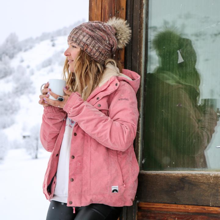 Jeune femme avec un chocolat chaud devant un chalet